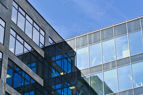 Detail of a modern office building with reflections in the windows and a blue sky in the background