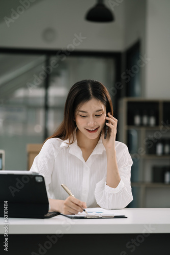 Business women talk mobile phones and working on laptop computers, online business.