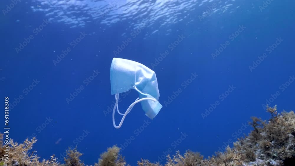Mascarilla flotando en el agua. Contaminación del mar