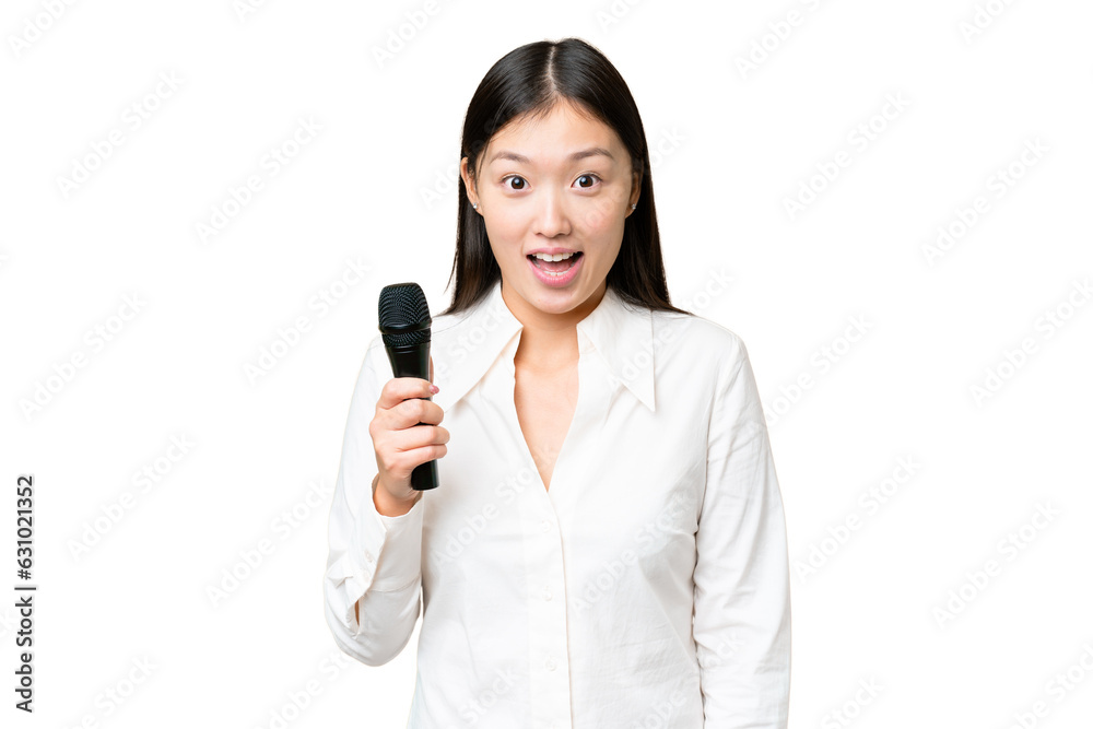 Singer picking up a microphone over isolated chroma key background with surprise and shocked facial expression Singer picking up a microphone over isolated chroma key background with surprise and shocked facial expression