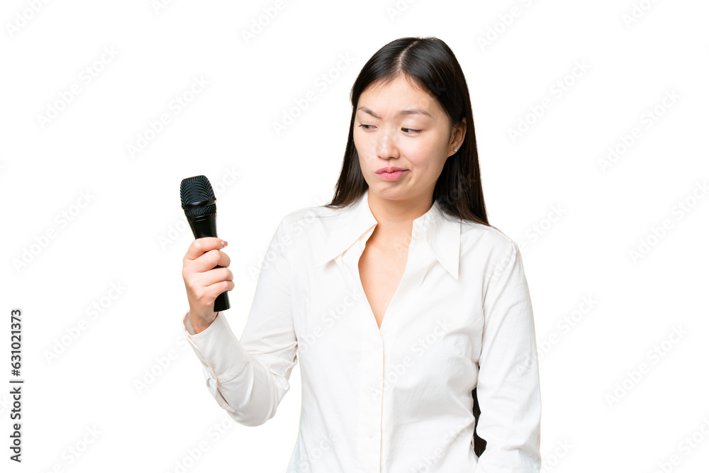 Singer picking up a microphone over isolated chroma key background with sad expression Singer picking up a microphone over isolated chroma key background with sad expression