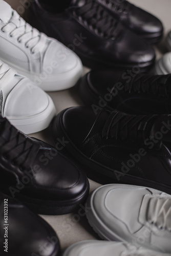Six pairs of black and white sneakers on the floor. Casual fashion style minimalistic shoes.
