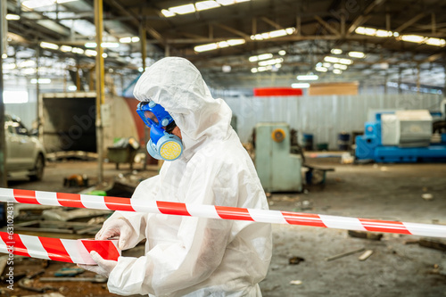 Man inspector scientist investigate chemical gas leak spill with safety face mask PPE suit in area closed barricade security red white tape. danger area infected toxic leak spill cross stripe ribbon © BESTIMAGE