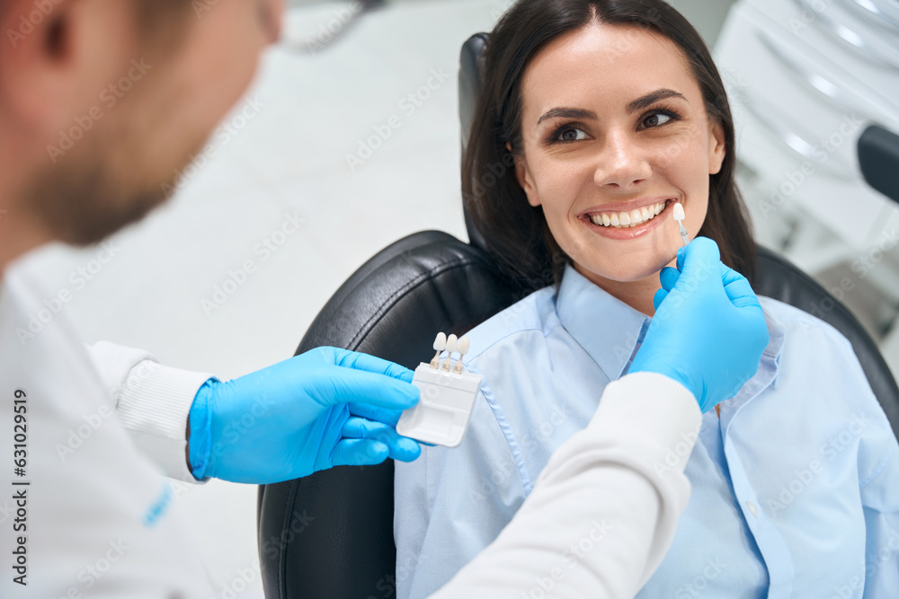 High-qualified dental technician choosing proper size and color of dental crown