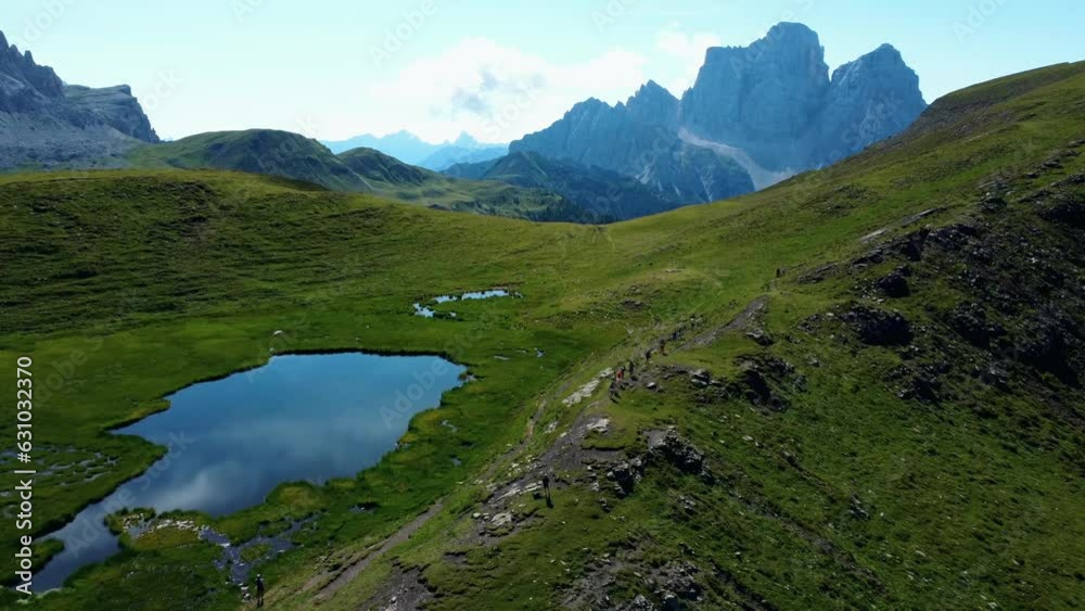 Aerial Shot Of Trail Runners Running In Dolomites Near Calm Blue Lake, Italy Aerial Shot Of Trail Runners Running In Dolomites Near Calm Blue Lake, Italy