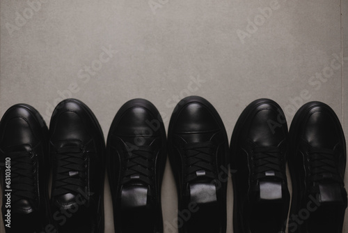 Three pairs of black sneakers on the floor. Casual fashion style minimalistic shoes.