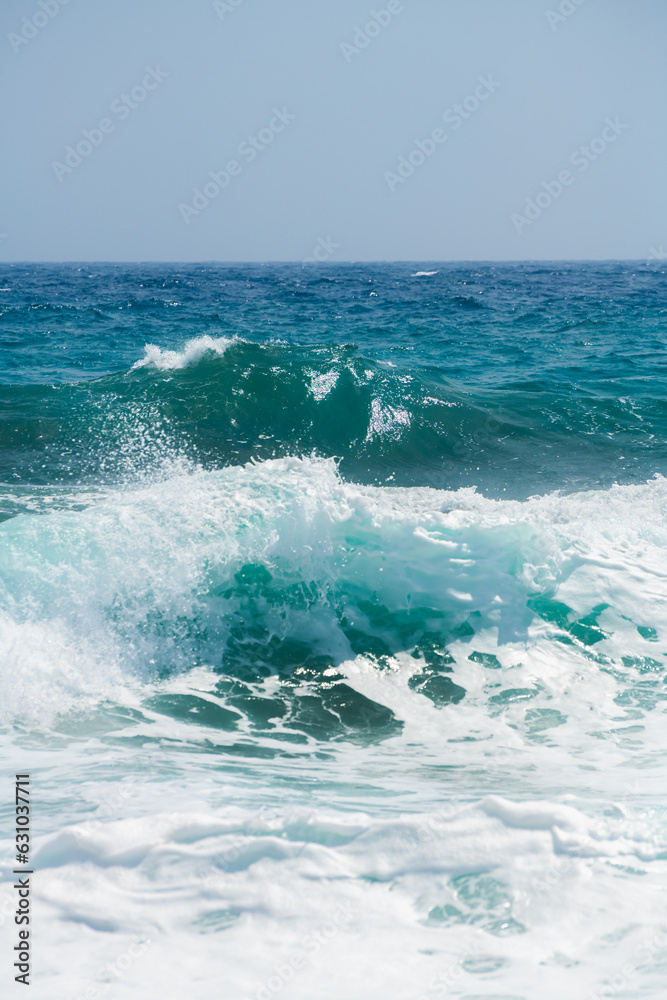 Waves on the beach in windy day. Santorini island, Greece. Blue sea and the blue sky.