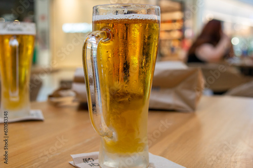 Cerveza en vaso frío tomada en una terraza de interior. Fondo desenfocado.