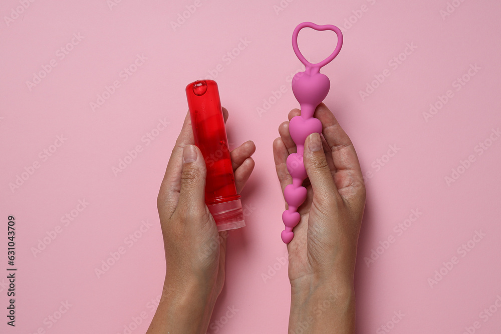 Lubricant with anal balls in hands on pink background - obrazy, fototapety, plakaty 