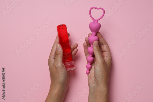 Lubricant with anal balls in hands on pink background photo
