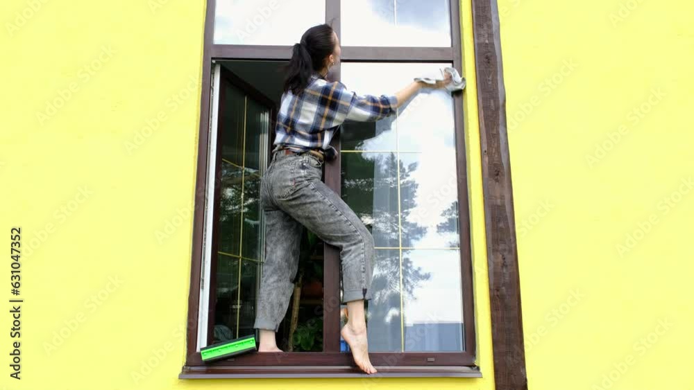 A woman manually washes the window of the house with a rag with a spray cleaner and a mop outside. Safety at height, restoring order and cleanliness in the spring, cleaning service A woman manually washes the window of the house with a rag with a spray cleaner and a mop outside. Safety at height, restoring order and cleanliness in the spring, cleaning service
