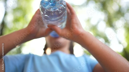 child drinking water from a plastic bottle. lifestyle water shortage problem on earth concept. water shortage problem on earth concept. kid drinks water in nature from a bottle glare of the sun summer