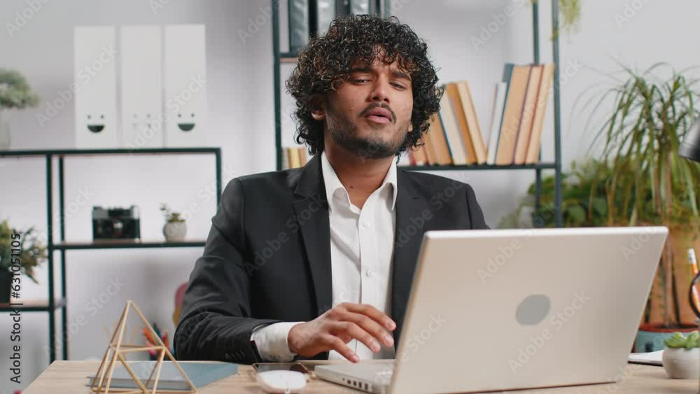 Indian businessman programmer software developer fingers crossed working on laptop loses becoming surprised by bad news results, fortune loss fail at home office. Deadline, bankruptcy. Freelancer man