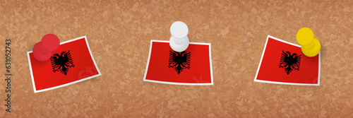 Albania flag pinned in cork board, three versions of Albania flag.