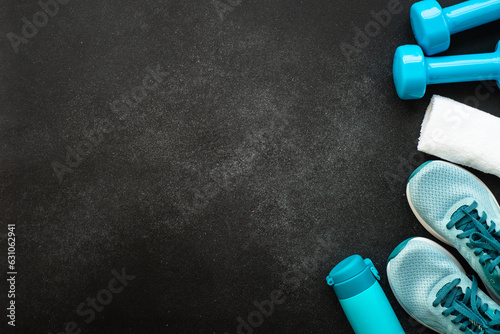 Workout and fitness concept, sport equipment. Sneakers, dumbbels and water bottle at black background. Flat lay with copy space. photo