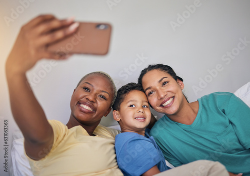 Gay family, happy and selfie in bed with foster boy child, bond and relax at home. Adoption, lesbian women and social media lgbt influencer smile for profile picture, blog or podcast post in bedroom