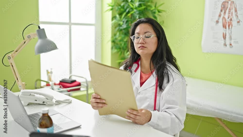 Young chinese woman doctor reading medical report at the clinic Young chinese woman doctor reading medical report at the clinic