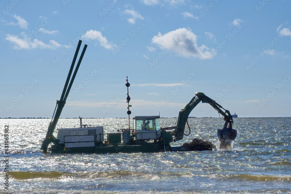 Fotografie A floating excavator digs mud in the water