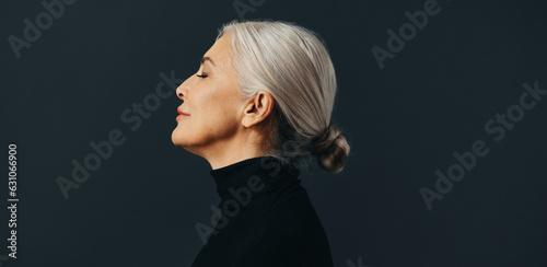 Side view of an empowered senior woman standing in studio