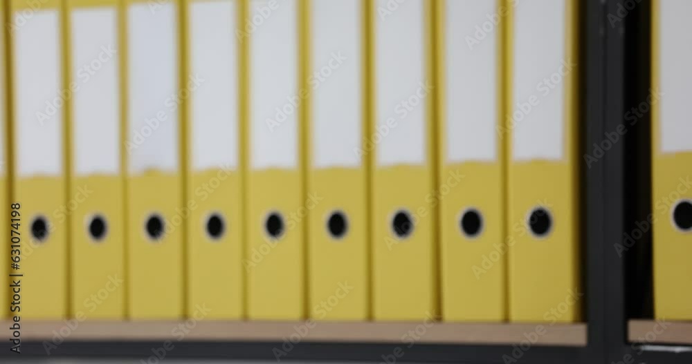 Yellow ring binders lined up on shelves in office archives. Accounting documents and business documents organized in folder structure in company Yellow ring binders lined up on shelves in office archives. Accounting documents and business documents organized in folder structure in company