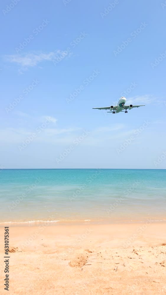 The airplane landing over a beautiful tropical beach and turquoise water in Phuket, Thailand. The plane landing at the resort. The airplane landing over a beautiful tropical beach and turquoise water in Phuket, Thailand. The plane landing at the resort.