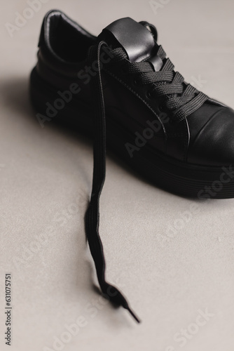 Close up details of black sneakers on the floor. Casual fashion style minimalistic shoes.