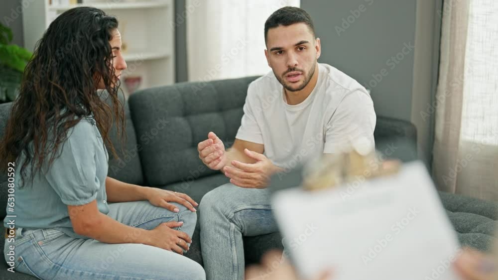 Man and woman sitting on sofa having couple therapy at psychology clinic Man and woman sitting on sofa having couple therapy at psychology clinic