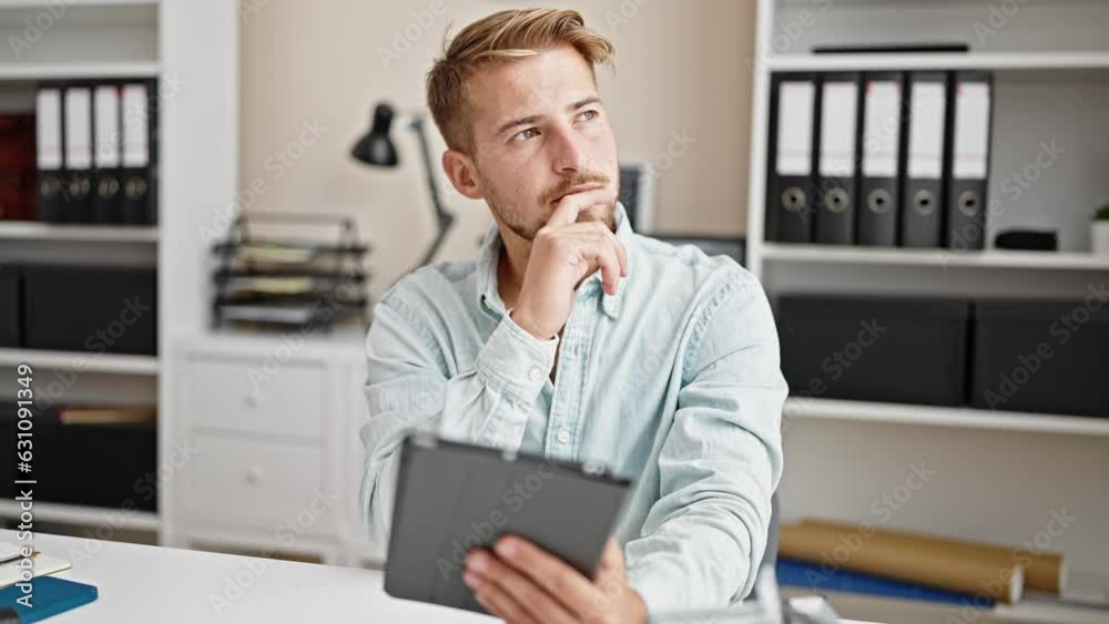Young caucasian man business worker using touchpad thinking at office Young caucasian man business worker using touchpad thinking at office