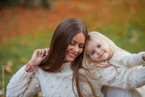 Beautiful young dark haired mother plays with her little daughter 3 years old in the autumn park. Walk. Family. Autumn.
