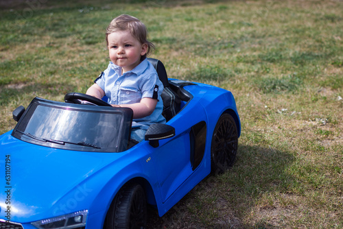 Baby fährt mit Kinderauto durch Garten