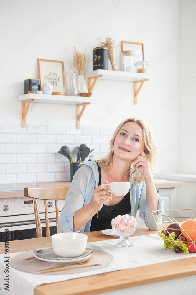 Happy beautiful woman with cup of coffee in the kitchen