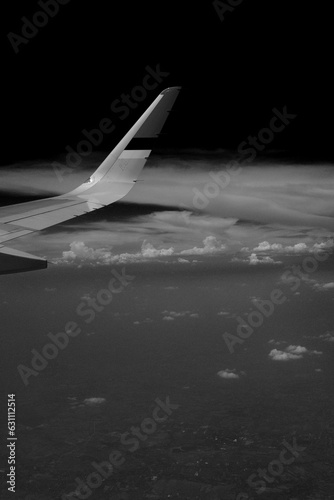 Black and white photo of a plane above the cloud