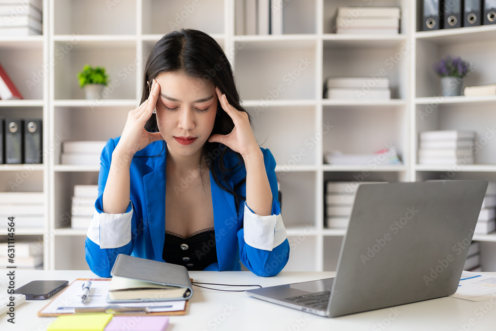 Asian women are stressed while working on laptops, tired, Asian businesswomen have headaches from looking at computer screens for too long at the office, feeling sick at work.