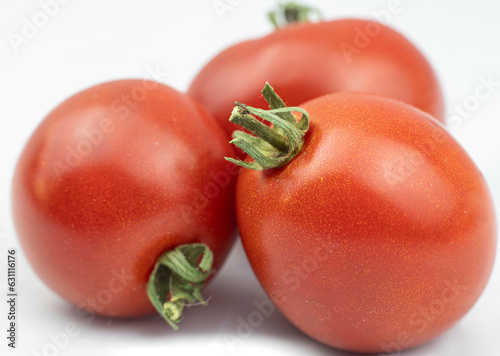 Obraz na płótnie Red tomatoes with green pedicel - three ripe fruits