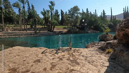 Pristine 4K stock video captures the natural beauty and serenity of a scenic lake surrounded by vegetation and cliffs in the Gan Hashlosha nature reserve in northern Israel, photo