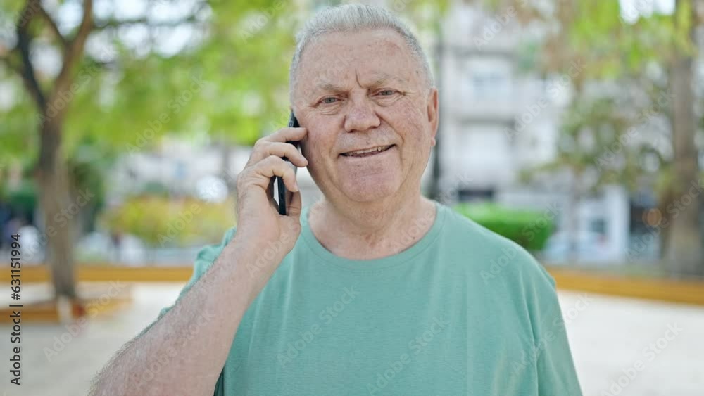 Middle age grey-haired man smiling confident talking on the smartphone at park Middle age grey-haired man smiling confident talking on the smartphone at park