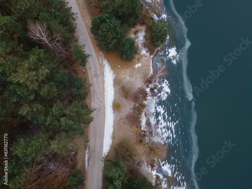 Aerial shot of a beach surrounded by the sea and greenery on a gloomy day