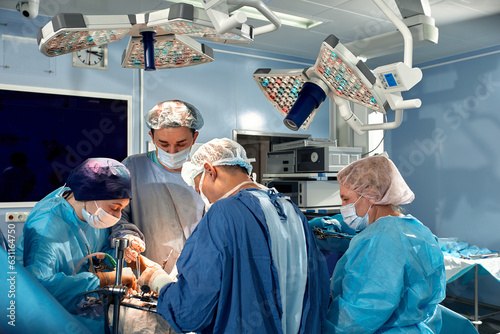 Surgeons team during complex surgical operation in a sterile operating room. Doctors leaned over patient using modern surgical instruments and clamps. Precision medicine, saving patient's life.