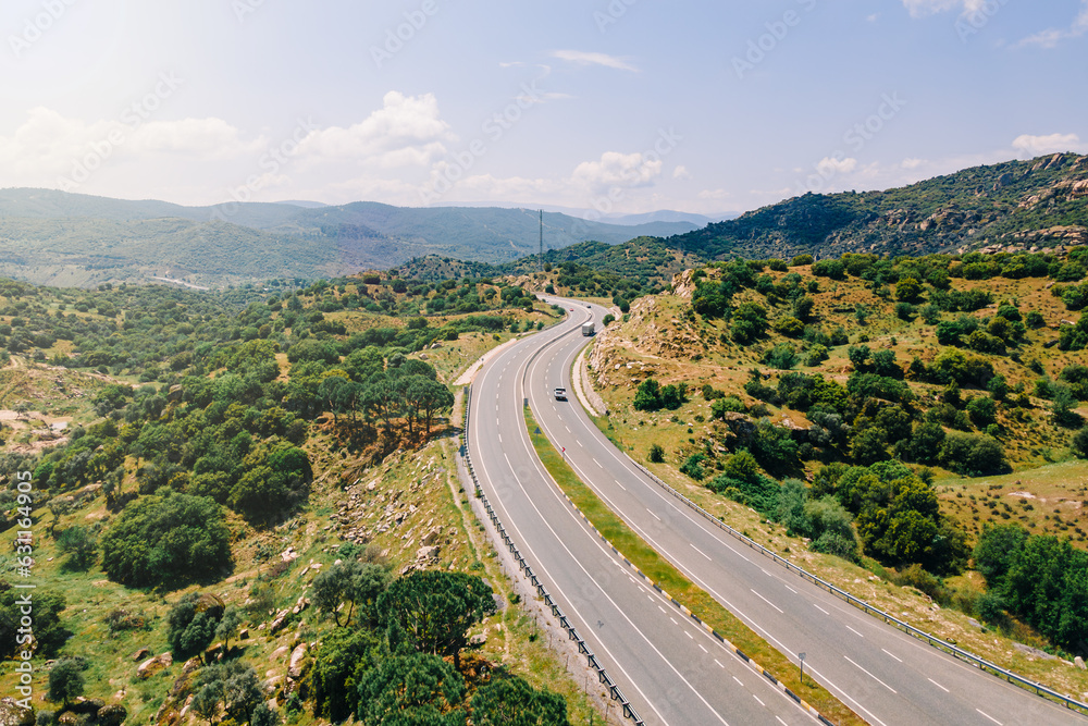 Aerial view over highway running between mountain and hills