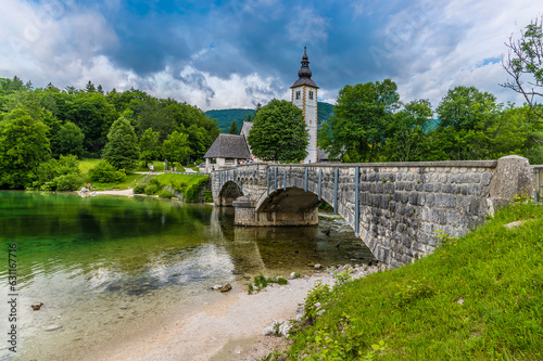 A view along the bridge at Bohinjsko Jezero towards the church of Saint John the Baptist in Slovenia in summertime