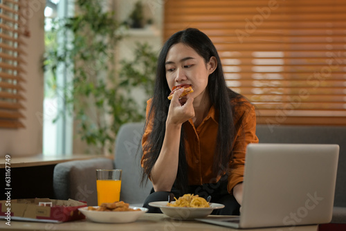 Asian woman eating spaghetti and laptop on table, working at home concept, domestic life
