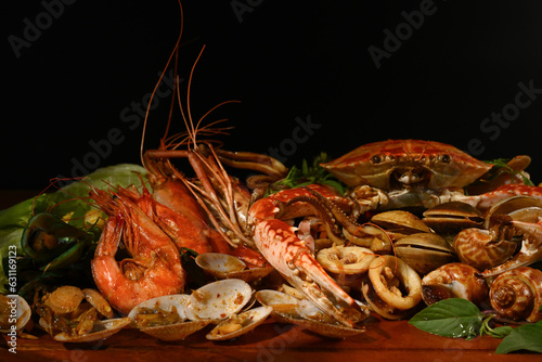 Mixed sea food on the wooden plate with black background.
