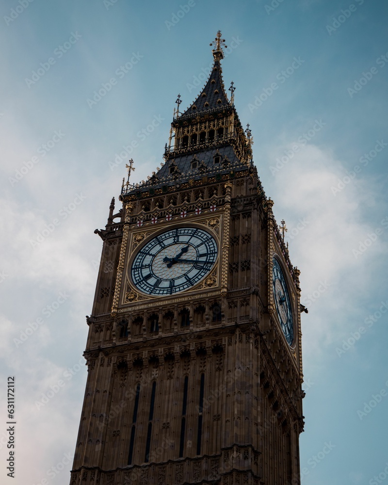 Antique Big Ben clock tower against a cloudy blue sky