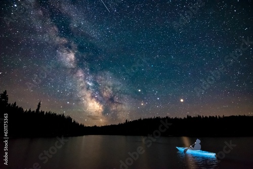 Leinwand Poster person in kayak watching night sky with stars in distance