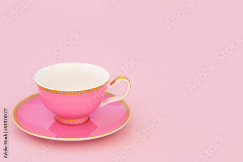 Pink and gold bone china tea cup. Elegant luxury drinking set on pastel pink background with copy space. Minimal zen composition.