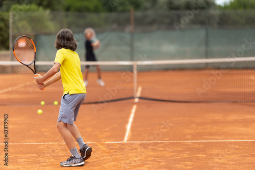 Two boys playing friendly tennis match on the court © KONSTANTIN SHISHKIN