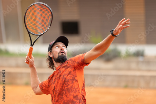 A man in red t-shirt playing tennis looking up © KONSTANTIN SHISHKIN