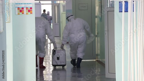 doctors in protective suit carry equipment in danger zone