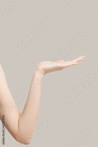 Female hand holding your product on beige background © Mirrorstudio