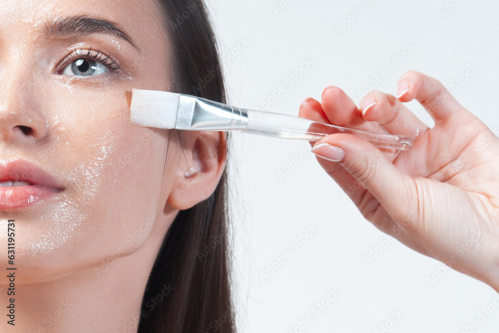 Young brunette woman applying moisturizing gel mask with brush on her face Young brunette woman applying moisturizing gel mask with brush on her face